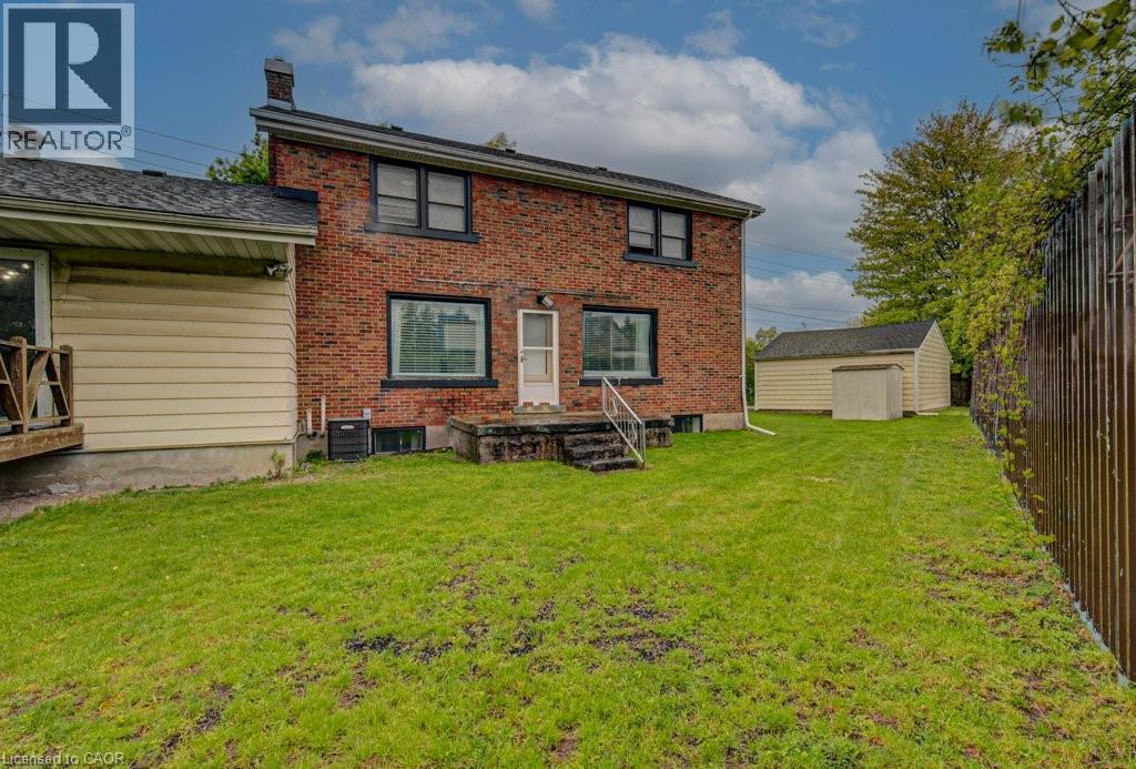 Brick exterior featuring a rear entry door with concrete steps and metal railings - 128 Pollock Avenue, Cambridge, ON - Outdoor With Exterior