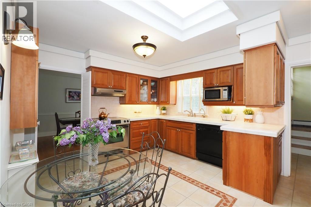 Kitchen featuring wood cabinetry, white countertops, a skylight, and tile flooring with an accent border - 2023 Coronation Boulevard, Cambridge, ON - Indoor Photo Showing Kitchen