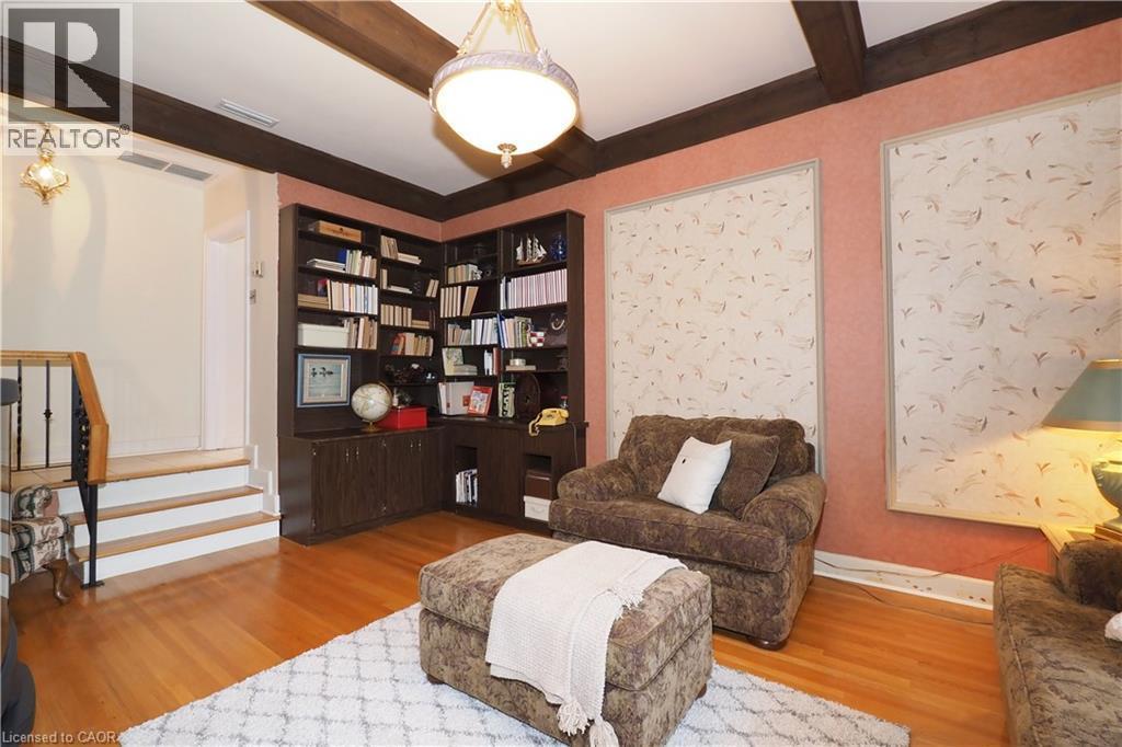 Room featuring corner built-in shelving, wood-finish flooring, exposed ceiling beams, and a semi-flush mount light fixture - 2023 Coronation Boulevard, Cambridge, ON - Indoor Photo Showing Living Room
