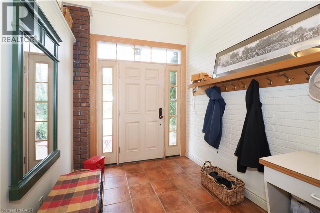 Entryway featuring terracotta-style tile flooring, a paneled entry door with sidelights and transom window, a white painted brick wall, and a built-in wood shelf with coat hooks - 2023 Coronation Boulevard, Cambridge, ON - Indoor Photo Showing Other Room