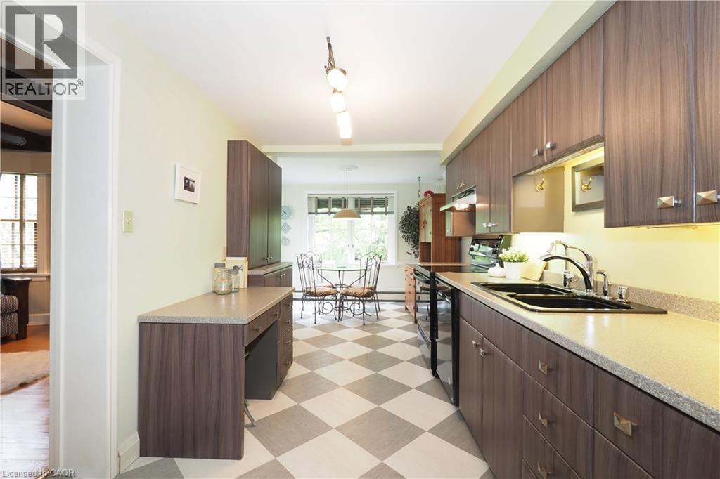 Galley kitchen featuring wood-finish cabinetry, light-toned countertops, and a checkered floor pattern - 2023 Coronation Boulevard, Cambridge, ON - Indoor Photo Showing Kitchen With Double Sink