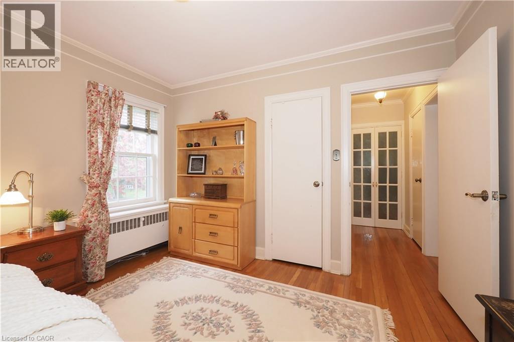 Hardwood flooring throughout, featuring crown molding, a window with blinds, and white interior doors - 2023 Coronation Boulevard, Cambridge, ON - Indoor Photo Showing Bedroom