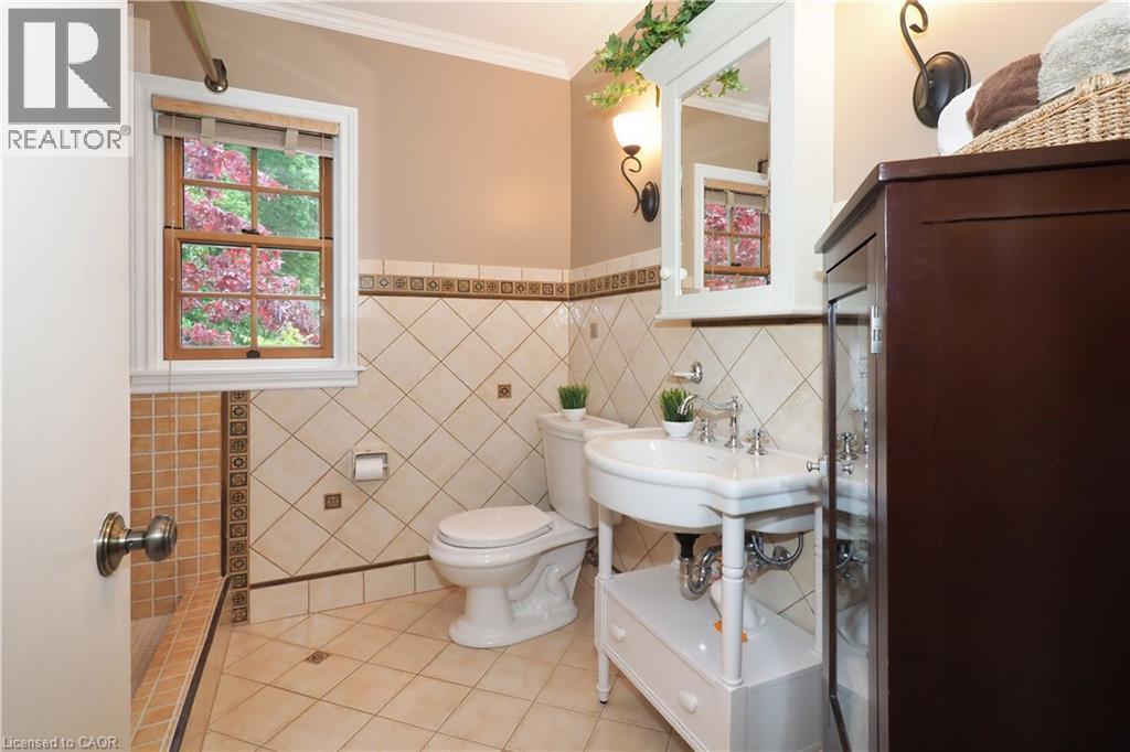 Bathroom featuring decorative tile work, a pedestal sink with chrome fixtures, and a wood-framed window - 2023 Coronation Boulevard, Cambridge, ON - Indoor Photo Showing Bathroom
