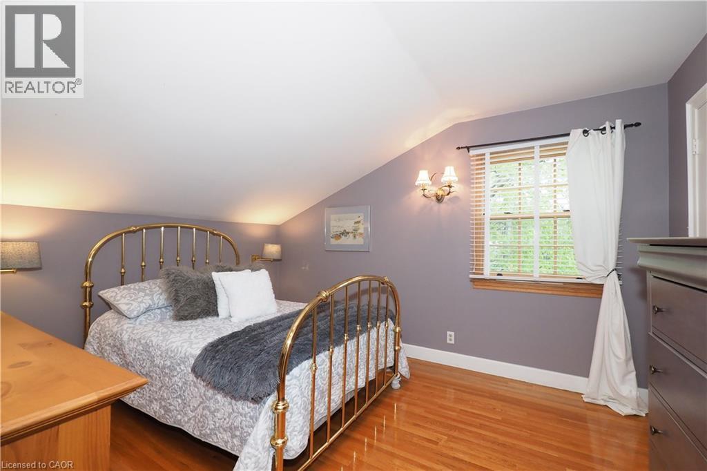 Room featuring sloped ceilings, wood-finish flooring, a double-hung window with blinds, and wall sconce lighting - 2023 Coronation Boulevard, Cambridge, ON - Indoor Photo Showing Bedroom