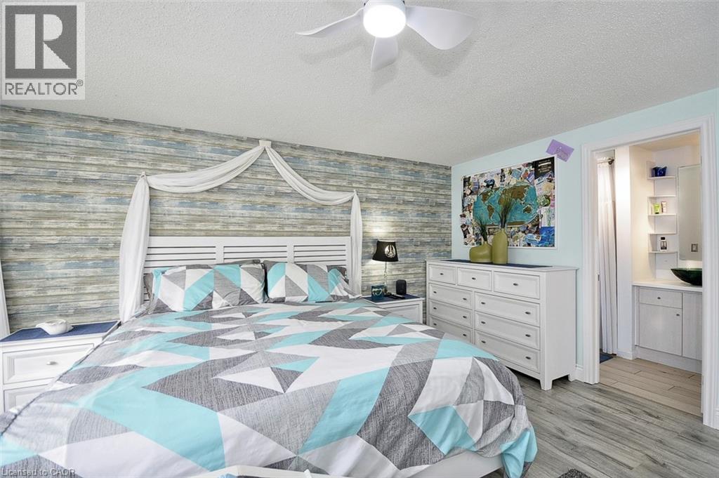 Bedroom featuring a decorative accent wall, ceiling fan, and wood-finish flooring - 12 Karalee Crescent, Cambridge, ON - Indoor Photo Showing Bedroom