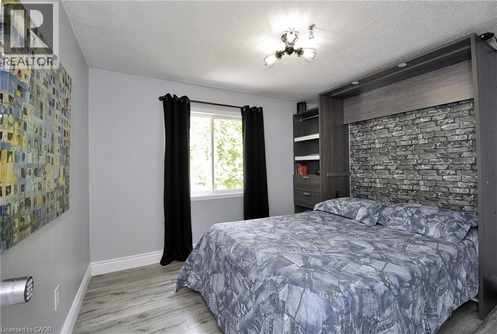 Compact sleeping area featuring a built-in wall unit with a stone-look accent panel, integrated shelving, and drawer storage - 12 Karalee Crescent, Cambridge, ON - Indoor Photo Showing Bedroom