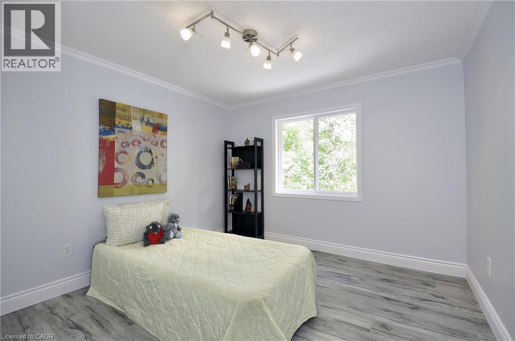 Bedroom featuring wood-finish flooring, a white-framed window, crown molding, track lighting, and light gray wall paint - 12 Karalee Crescent, Cambridge, ON - Indoor Photo Showing Bedroom