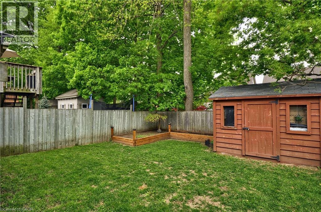 Expansive backyard featuring a manicured lawn, a wood-sided storage shed with double doors, and a raised garden bed - 12 Karalee Crescent, Cambridge, ON - Outdoor
