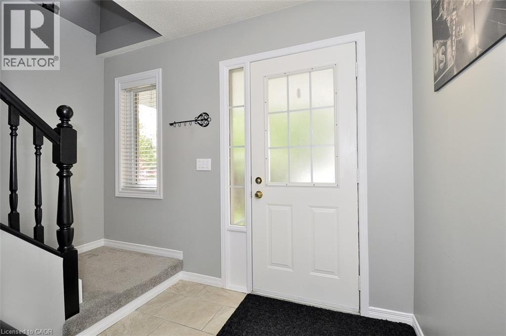 Entryway featuring a white door with frosted glass panels and a sidelight, neutral wall tones, and a staircase with dark wood balusters and a carpeted tread - 12 Karalee Crescent, Cambridge, ON - Indoor Photo Showing Other Room