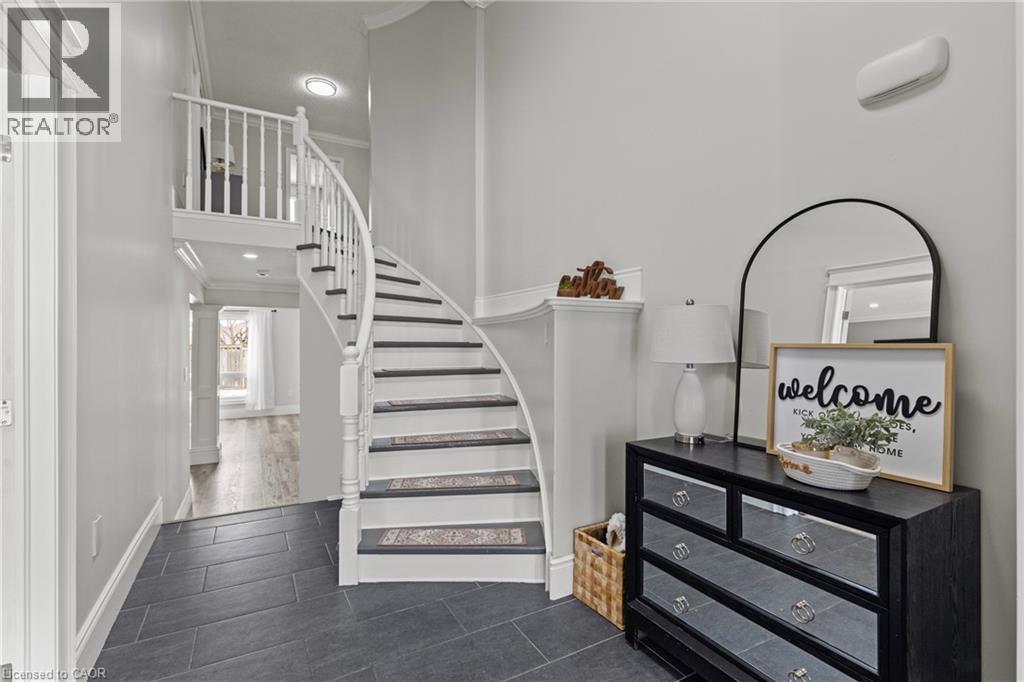 Elegant foyer featuring a curved staircase with white risers and dark treads, slate-look tile flooring, white balusters, and a recessed ceiling light - 27 Barbara Court, Hamilton, ON - Indoor Photo Showing Other Room