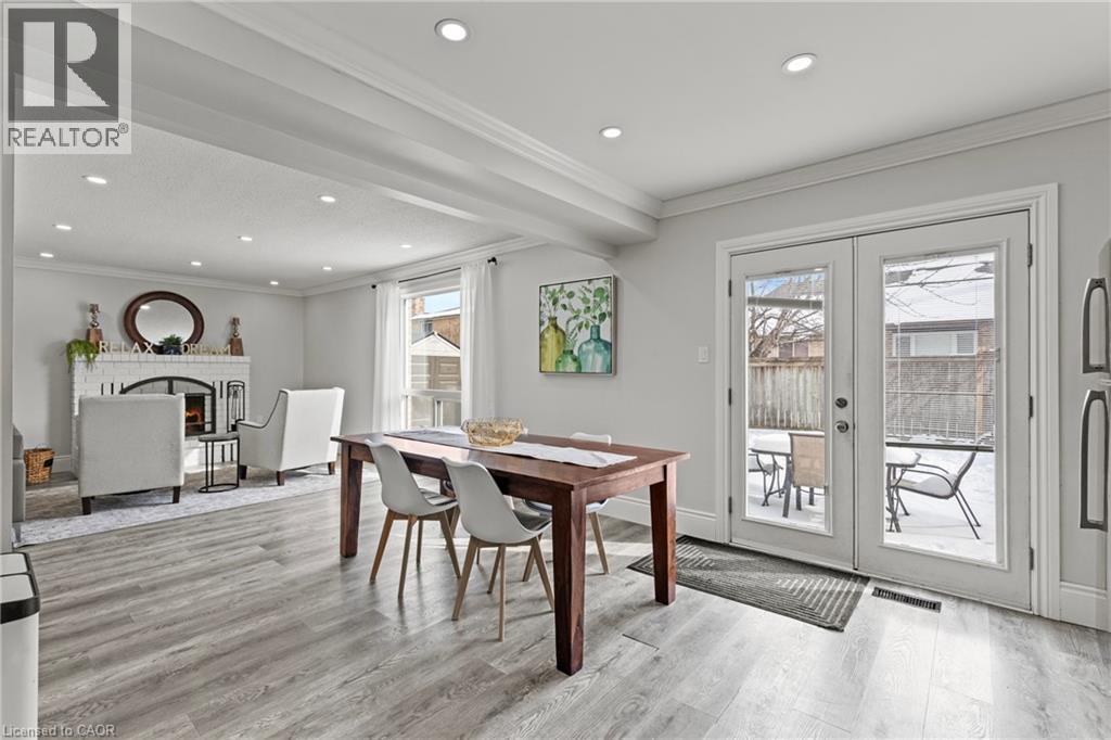 Open-concept living area with light wood-finish flooring, recessed lighting, white trim, and a white brick fireplace - 27 Barbara Court, Hamilton, ON - Indoor Photo Showing Other Room