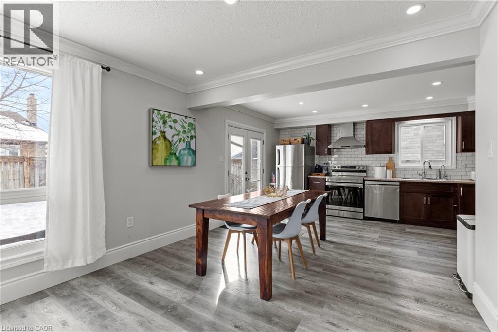 Open-concept kitchen and dining area featuring wood-finish flooring, recessed lighting, and crown molding - 27 Barbara Court, Hamilton, ON - Indoor