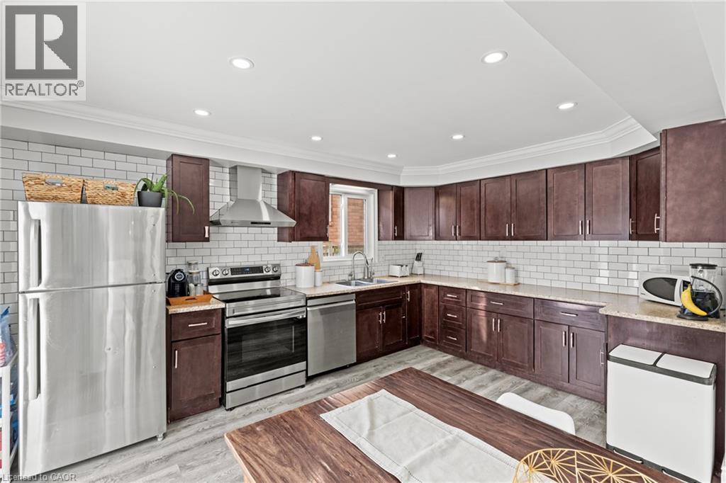 Kitchen featuring wood-finish cabinetry, stainless steel appliances, subway tile backsplash, and light-toned countertops - 27 Barbara Court, Hamilton, ON - Indoor Photo Showing Kitchen With Double Sink With Upgraded Kitchen