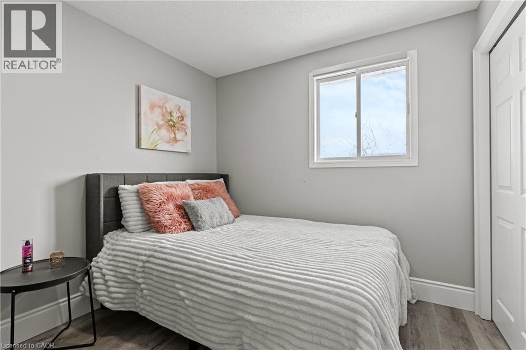 Neutral gray wall paint, wood-finish flooring, white trim, and a white interior door with paneling - 27 Barbara Court, Hamilton, ON - Indoor Photo Showing Bedroom