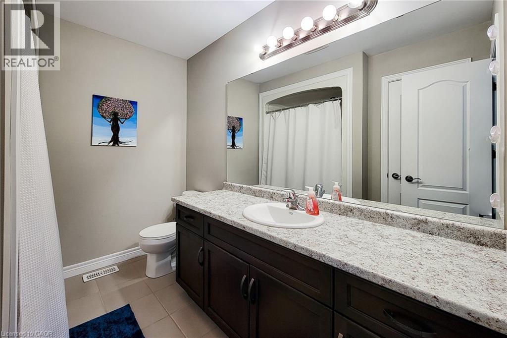 Bathroom featuring a dark wood-finish vanity with a light speckled countertop, an integrated sink, and an expansive mirror - 40 Fairgrounds Drive, Binbrook, ON - Indoor Photo Showing Bathroom