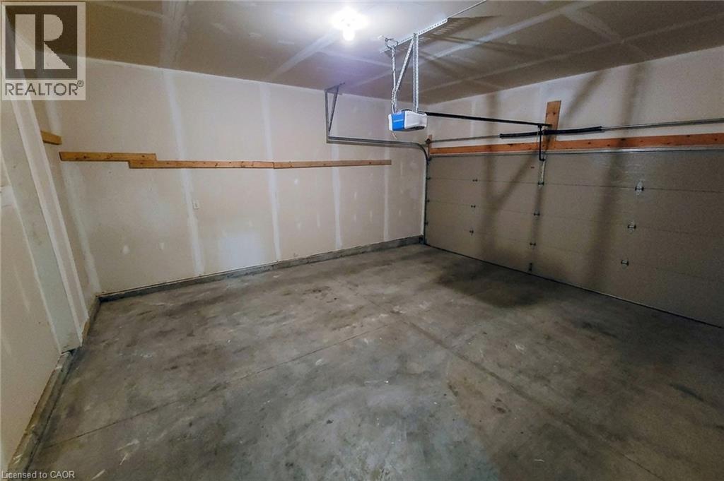 Spacious garage featuring a concrete floor, overhead lighting, an automatic garage door opener, and integrated wall shelving - 40 Fairgrounds Drive, Binbrook, ON - Indoor Photo Showing Garage