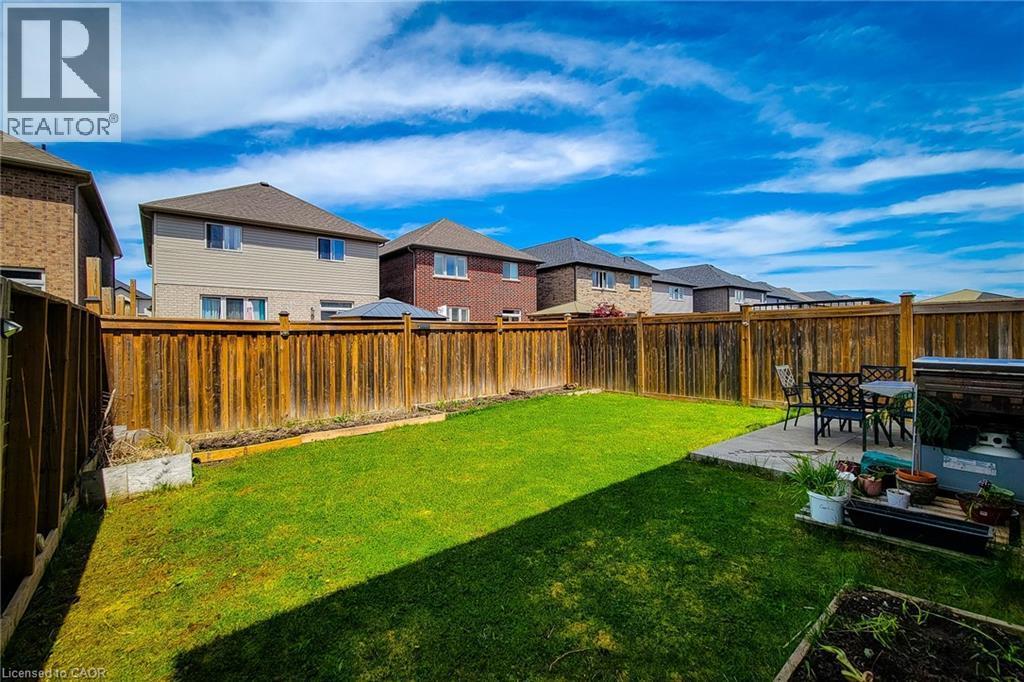 Expansive backyard with a manicured lawn, a concrete patio, and privacy fencing - 40 Fairgrounds Drive, Binbrook, ON - Outdoor
