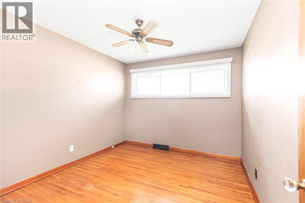 Hardwood flooring throughout, complemented by a ceiling fan with integrated lighting - 435 East 36Th Street, Hamilton, ON - Indoor Photo Showing Other Room