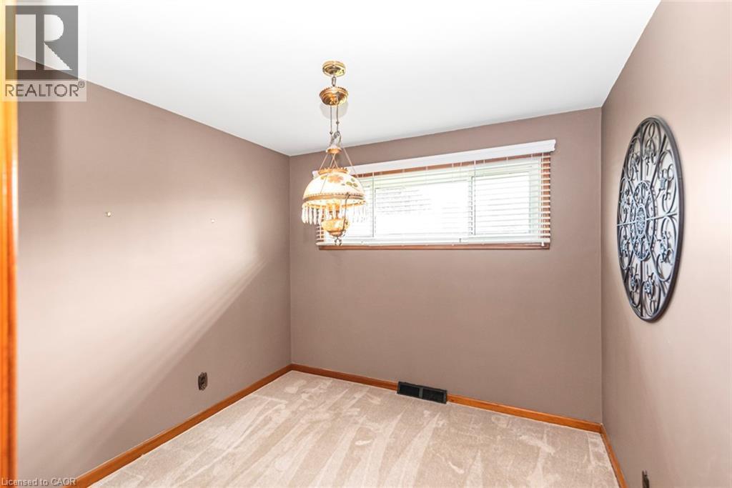 Carpeted room featuring a single window with blinds, a classic chandelier, and wood-finish trim - 435 East 36Th Street, Hamilton, ON - Indoor Photo Showing Other Room
