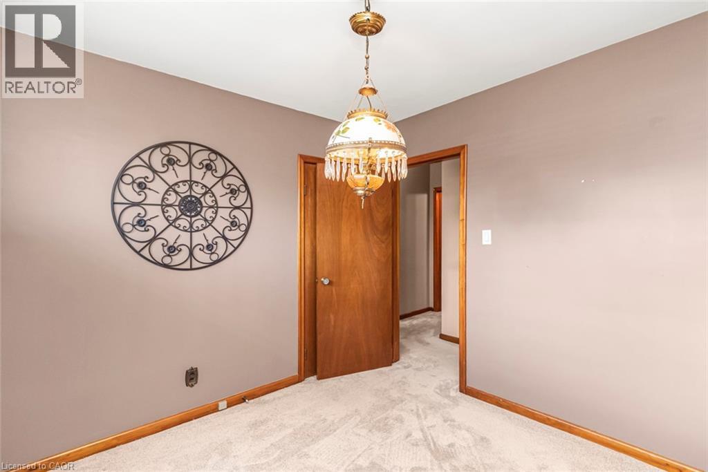 Carpeted room featuring a ceiling-mounted chandelier, wood-finish doors, and wood-finish baseboards - 435 East 36Th Street, Hamilton, ON - Indoor Photo Showing Other Room