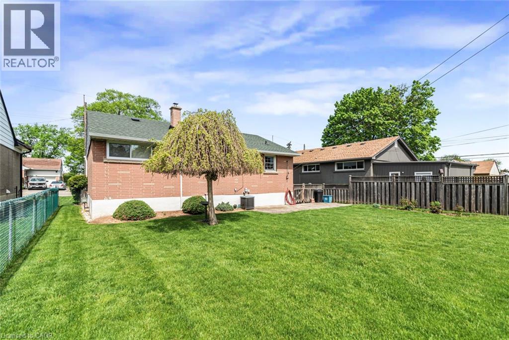 Expansive backyard featuring a manicured lawn, a concrete patio, and a mature weeping willow tree - 435 East 36Th Street, Hamilton, ON - Outdoor
