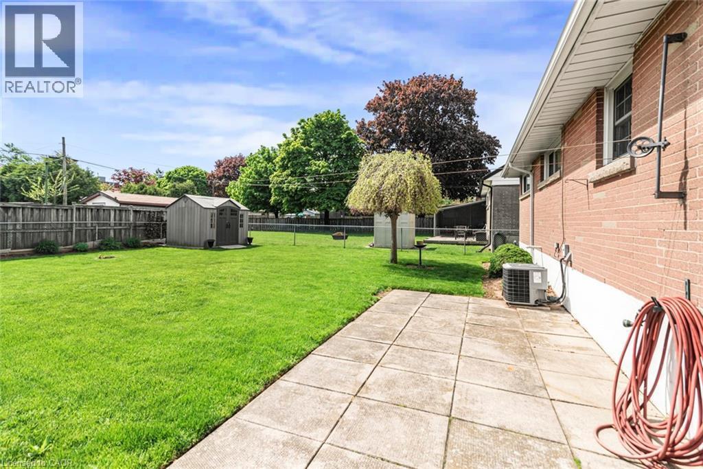 Expansive green lawn with a patio featuring square pavers, a red brick exterior, and a built-in storage shed - 435 East 36Th Street, Hamilton, ON - Outdoor