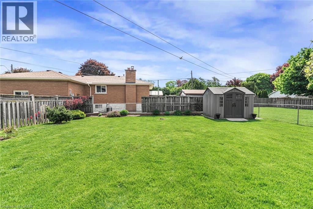 Expansive green lawn featuring a storage shed with double doors, wood fencing, and a chain-link fence - 435 East 36Th Street, Hamilton, ON - Outdoor
