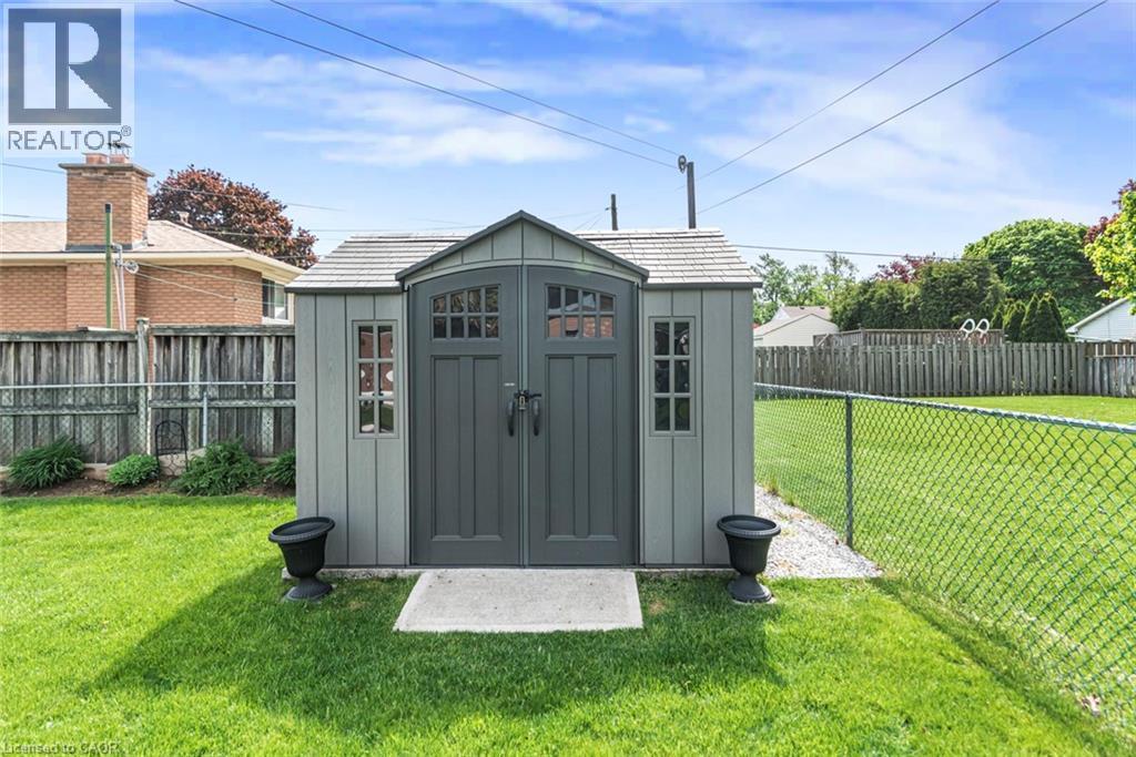 Freestanding storage shed featuring double doors with window panes, side windows, and a shingled roof - 435 East 36Th Street, Hamilton, ON - Outdoor