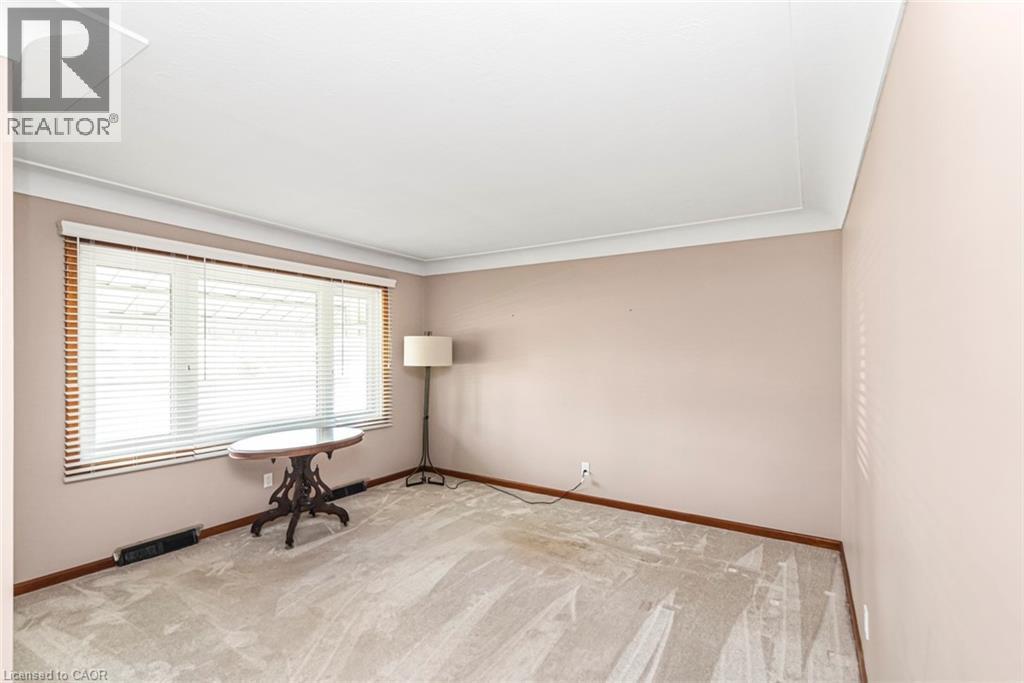 Bright interior space featuring a large window with horizontal blinds, neutral wall tones, white crown molding, and light-toned carpeting - 435 East 36Th Street, Hamilton, ON - Indoor Photo Showing Other Room