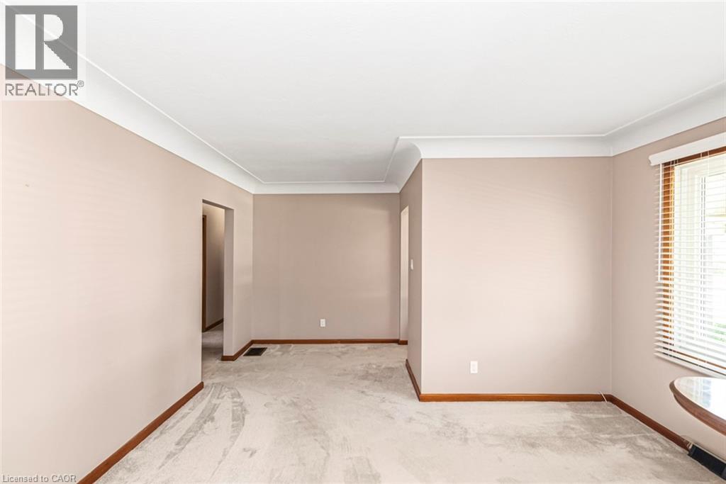 Spacious interior room featuring light gray carpeting, neutral wall tones, white crown molding, and wood-finish baseboards - 435 East 36Th Street, Hamilton, ON - Indoor Photo Showing Other Room