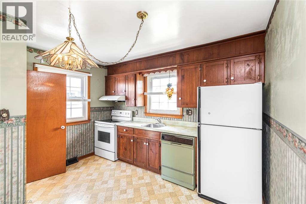 Kitchen featuring wood cabinetry, a built-in range hood, and two windows - 435 East 36Th Street, Hamilton, ON - Indoor Photo Showing Kitchen