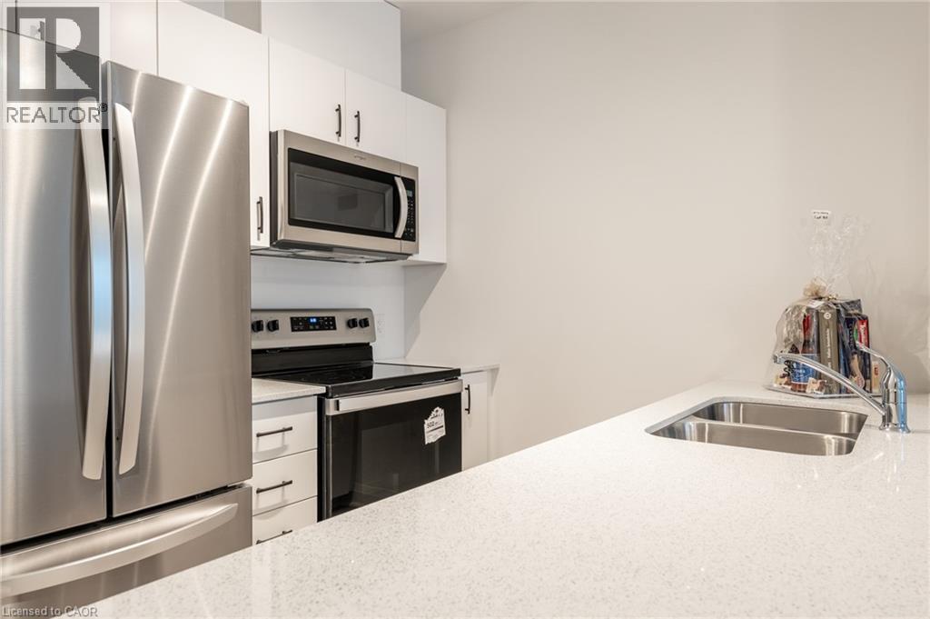 Kitchen featuring stainless steel appliances, white cabinetry, a dual basin sink, and a light-toned countertop - 1936 Rymal Road E Unit# 512, Hamilton, ON - Indoor Photo Showing Kitchen With Stainless Steel Kitchen With Double Sink