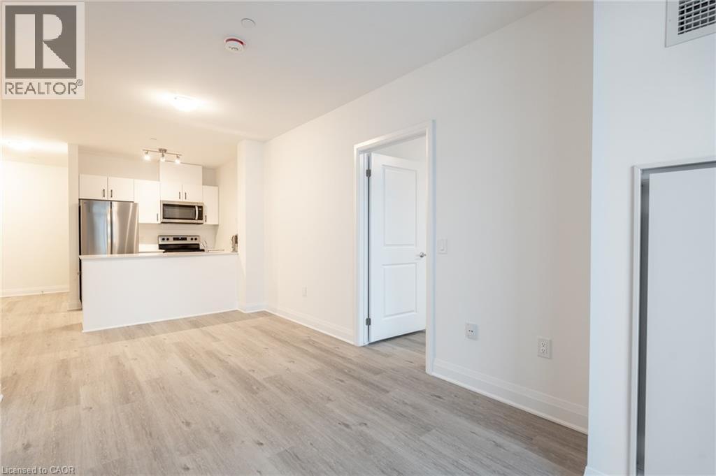 Open-concept living space featuring wood-finish flooring, white baseboards, and neutral wall paint - 1936 Rymal Road E Unit# 512, Hamilton, ON - Indoor Photo Showing Kitchen
