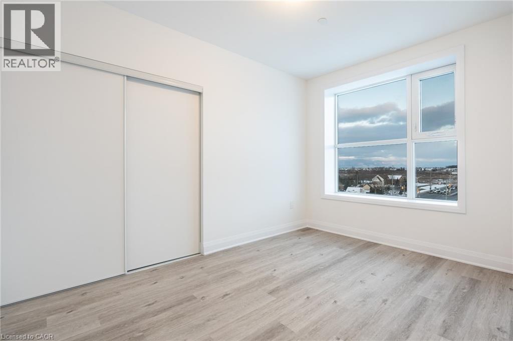 Light wood-finish flooring with white baseboards and neutral wall paint - 1936 Rymal Road E Unit# 512, Hamilton, ON - Indoor Photo Showing Other Room