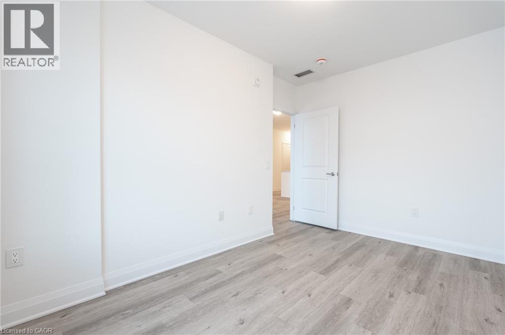Spacious room featuring light wood-finish flooring and crisp white walls - 1936 Rymal Road E Unit# 512, Hamilton, ON - Indoor Photo Showing Other Room