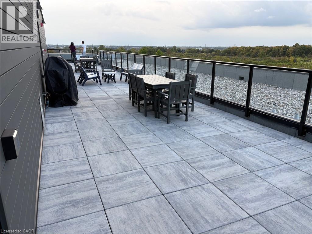Spacious rooftop patio featuring large format pavers, modern glass railings, and expansive exterior siding - 1936 Rymal Road E Unit# 512, Hamilton, ON - Outdoor With Exterior