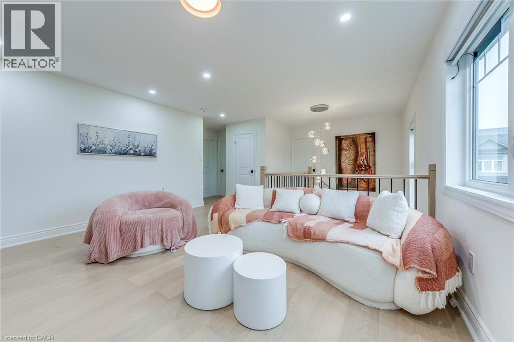 Bright open concept area featuring light wood-finish flooring, recessed lighting, a large window, and a wood and metal railing - 3937 Leonardo Street, Burlington, ON - Indoor Photo Showing Living Room
