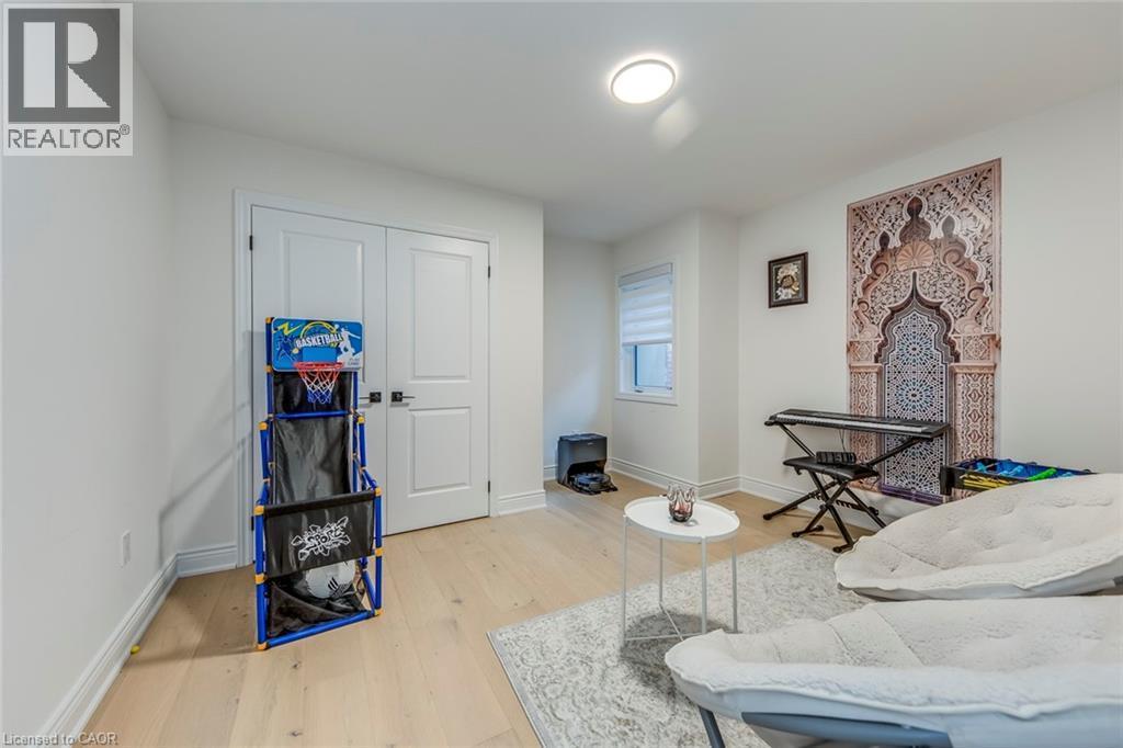 Spacious room featuring light wood-finish flooring, white walls, and a contemporary flush-mount ceiling light - 3937 Leonardo Street, Burlington, ON - Indoor