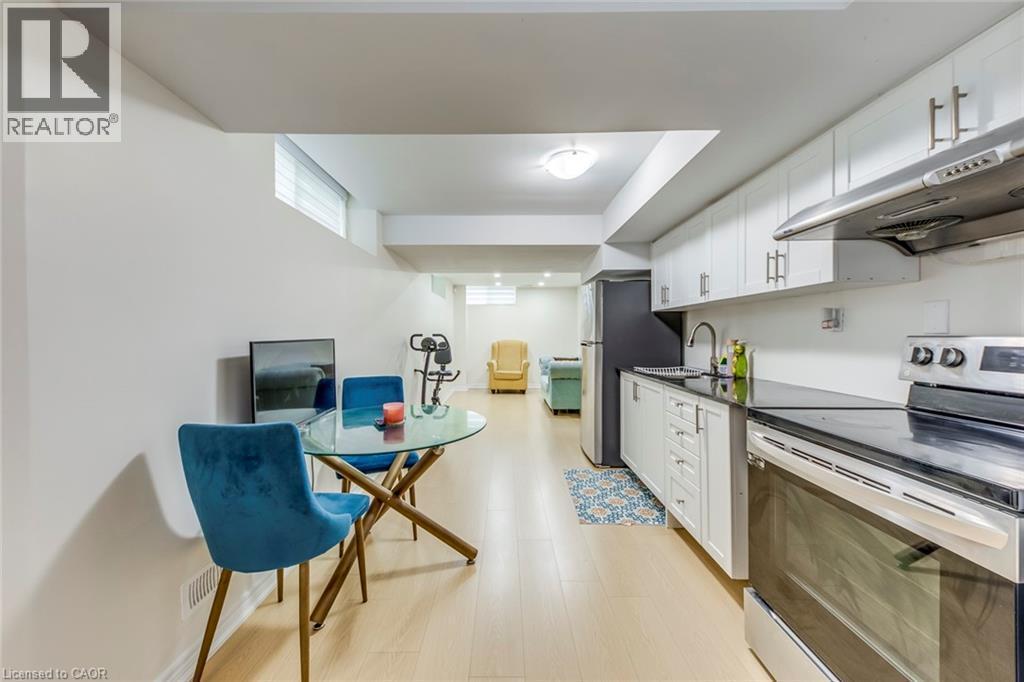 Kitchenette featuring white cabinetry, black countertops, stainless steel appliances, and a stainless steel sink with a gooseneck faucet - 3937 Leonardo Street, Burlington, ON - Indoor Photo Showing Kitchen