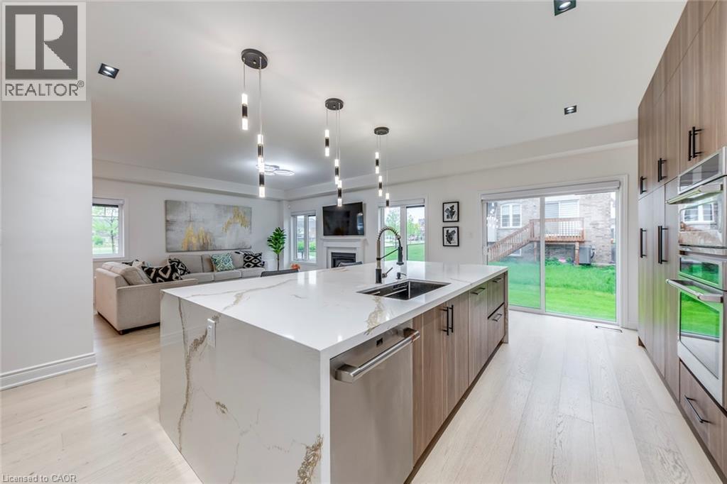 Expansive kitchen island with a waterfall countertop, integrated sink, and dishwasher - 3937 Leonardo Street, Burlington, ON - Indoor Photo Showing Kitchen With Upgraded Kitchen