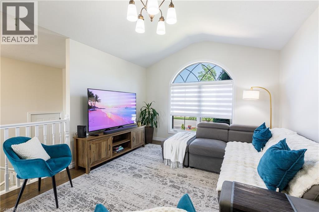 Vaulted ceiling living area featuring a large arched window with decorative muntins, wood-finish flooring, and a white spindle railing - 10 Redbud Crescent, Simcoe, ON - Indoor Photo Showing Bedroom