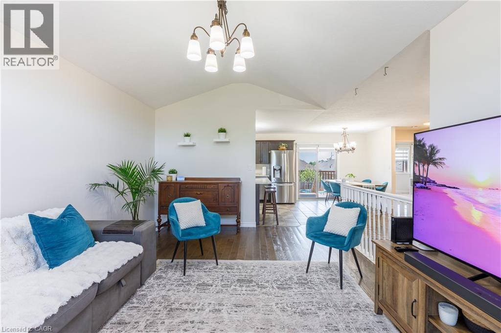 Vaulted ceilings enhance the living area, featuring wood-finish flooring and a contemporary chandelier - 10 Redbud Crescent, Simcoe, ON - Indoor