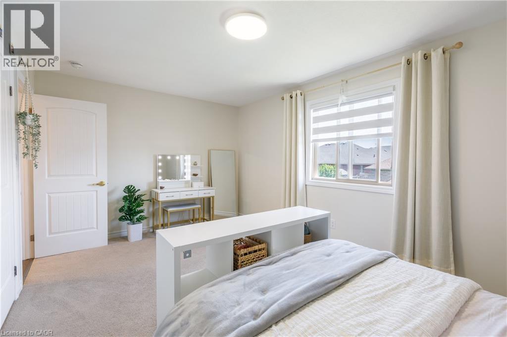 Carpeted room featuring a window with horizontal blinds and curtains, a white paneled door, and a flush-mount ceiling light - 10 Redbud Crescent, Simcoe, ON - Indoor Photo Showing Bedroom