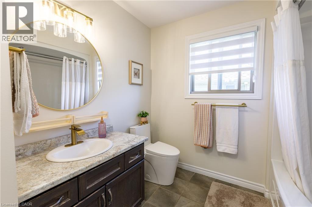 Bathroom featuring a dark wood-finish vanity with an oval sink, a light-toned countertop, and a gold-finish faucet - 10 Redbud Crescent, Simcoe, ON - Indoor Photo Showing Bathroom