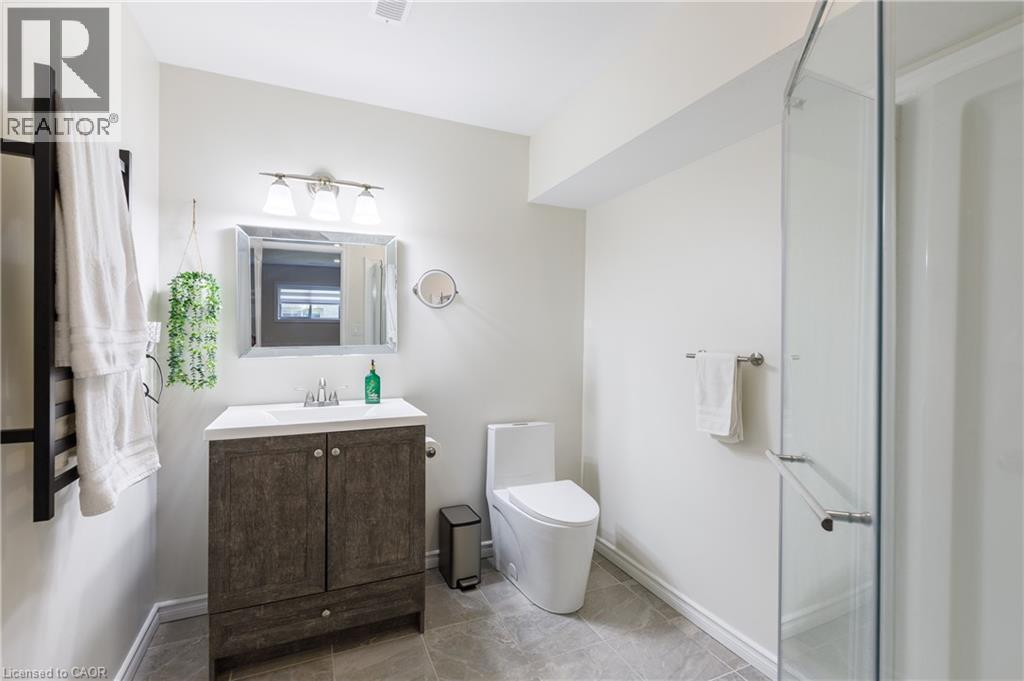 Bathroom featuring a modern vanity with a white countertop and wood-finish cabinetry, a contemporary toilet, and a glass-enclosed shower - 10 Redbud Crescent, Simcoe, ON - Indoor Photo Showing Bathroom
