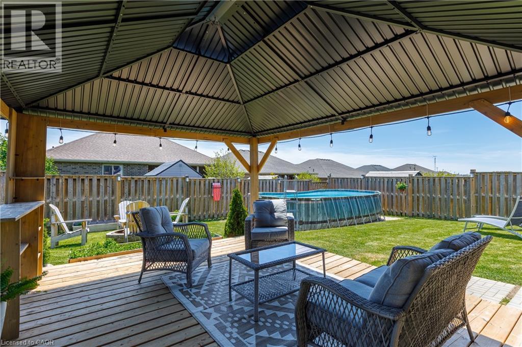 Expansive backyard featuring a covered patio with string lighting, wood deck, and a privacy fence - 10 Redbud Crescent, Simcoe, ON - Outdoor With Deck Patio Veranda With Exterior