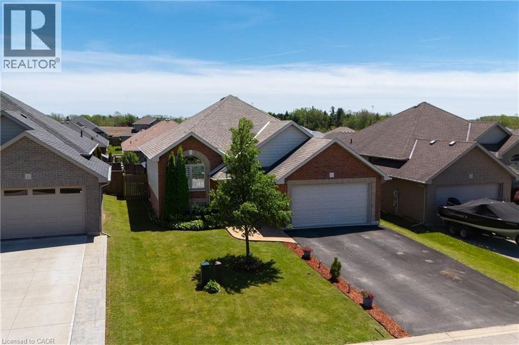 Brick exterior residence featuring an attached garage, paved driveway, and manicured front lawn - 10 Redbud Crescent, Simcoe, ON - Outdoor With Facade