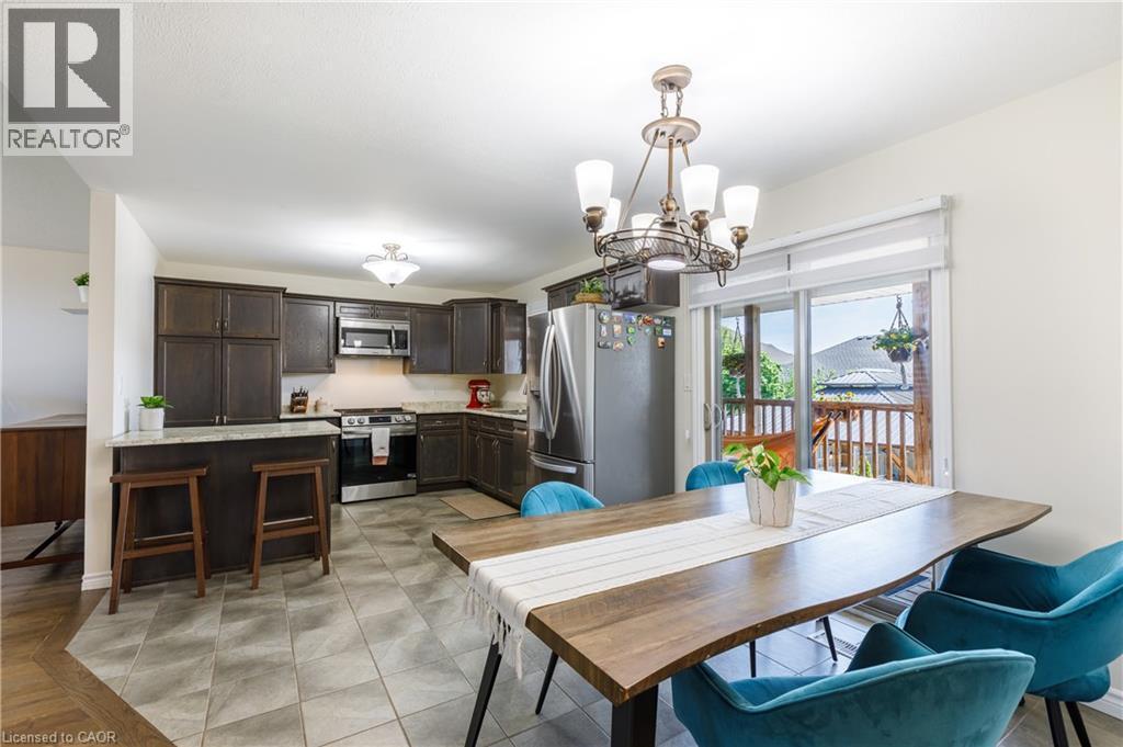 Open-concept kitchen and dining area featuring dark wood-finish cabinetry, stainless steel appliances, and light-toned tile flooring - 10 Redbud Crescent, Simcoe, ON - Indoor Photo Showing Dining Room