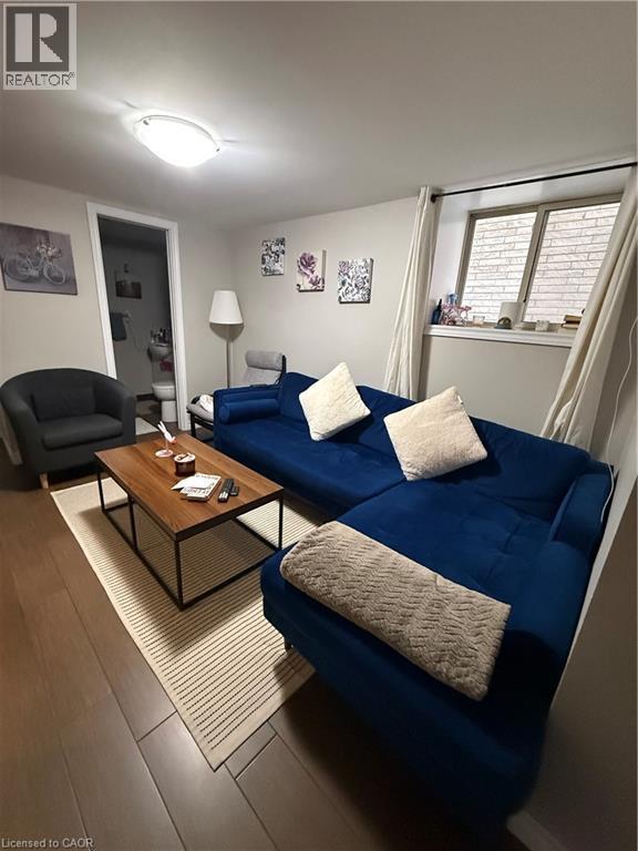 Spacious room featuring wood-finish flooring, a contemporary flush-mount ceiling light, and a window with brick-patterned glass - 947 Main Street E Unit# 6, Hamilton, ON - Indoor Photo Showing Living Room