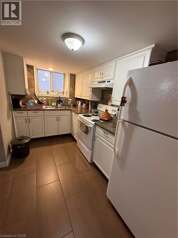 Kitchen featuring wood-finish tile flooring, white cabinetry, integrated appliances, and a window for natural light - 947 Main Street E Unit# 6, Hamilton, ON - Indoor Photo Showing Kitchen